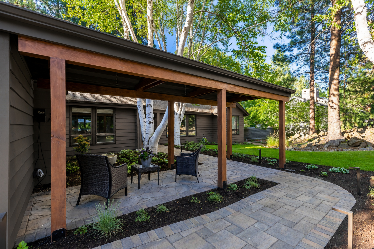 Mountain High — covered side patio with wicker chairs, flagstone, and birch trees