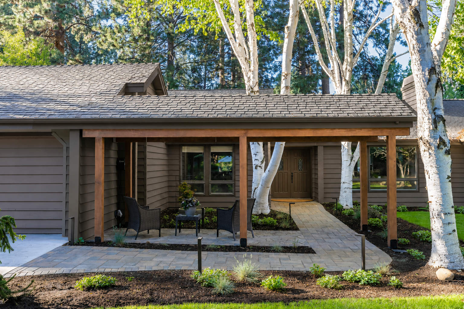 Mountain High — front elevation close-up showing cedar pergola, birch trees, and paver walkway