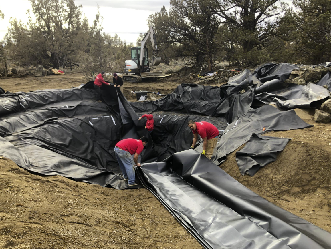 East Bend — construction: crew laying pond liner with excavator