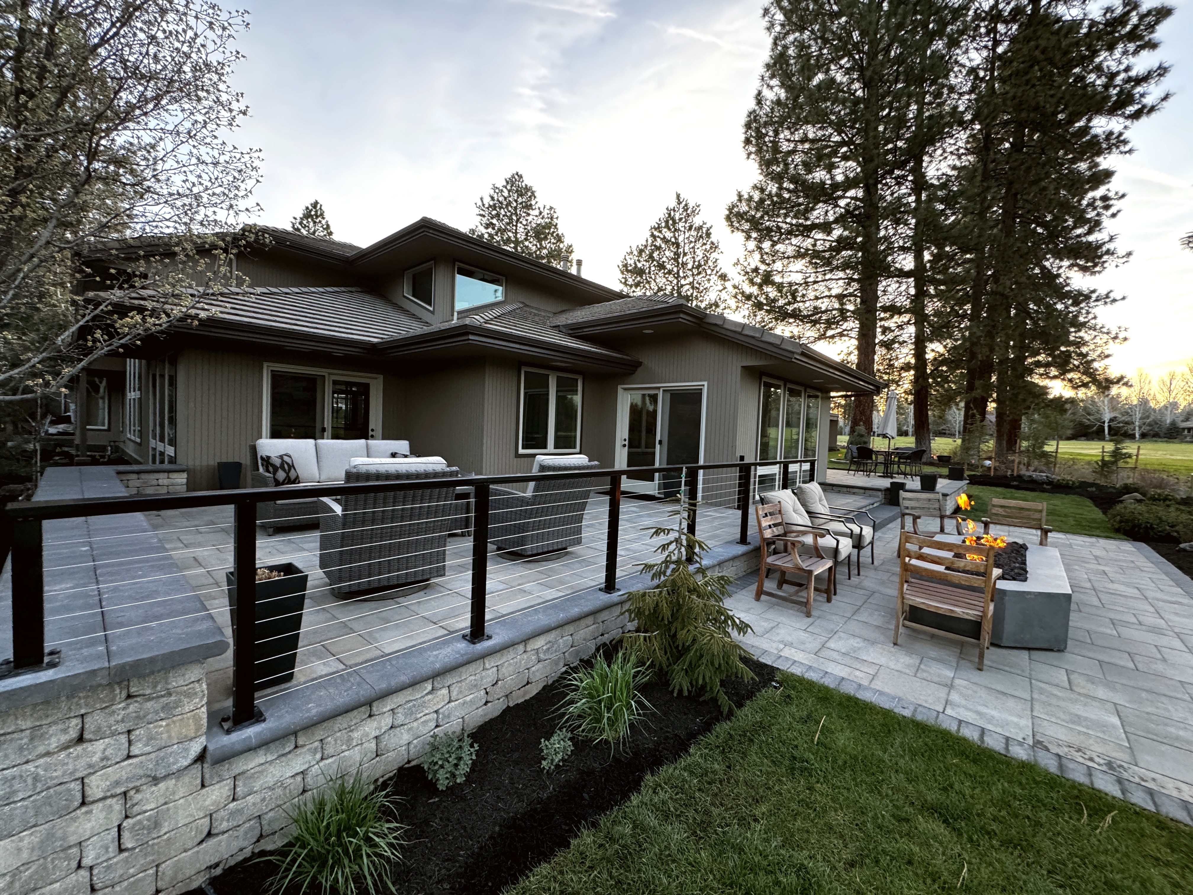 Paver patio with fire pit and outdoor seating at dusk in Broken Top Bend Oregon
