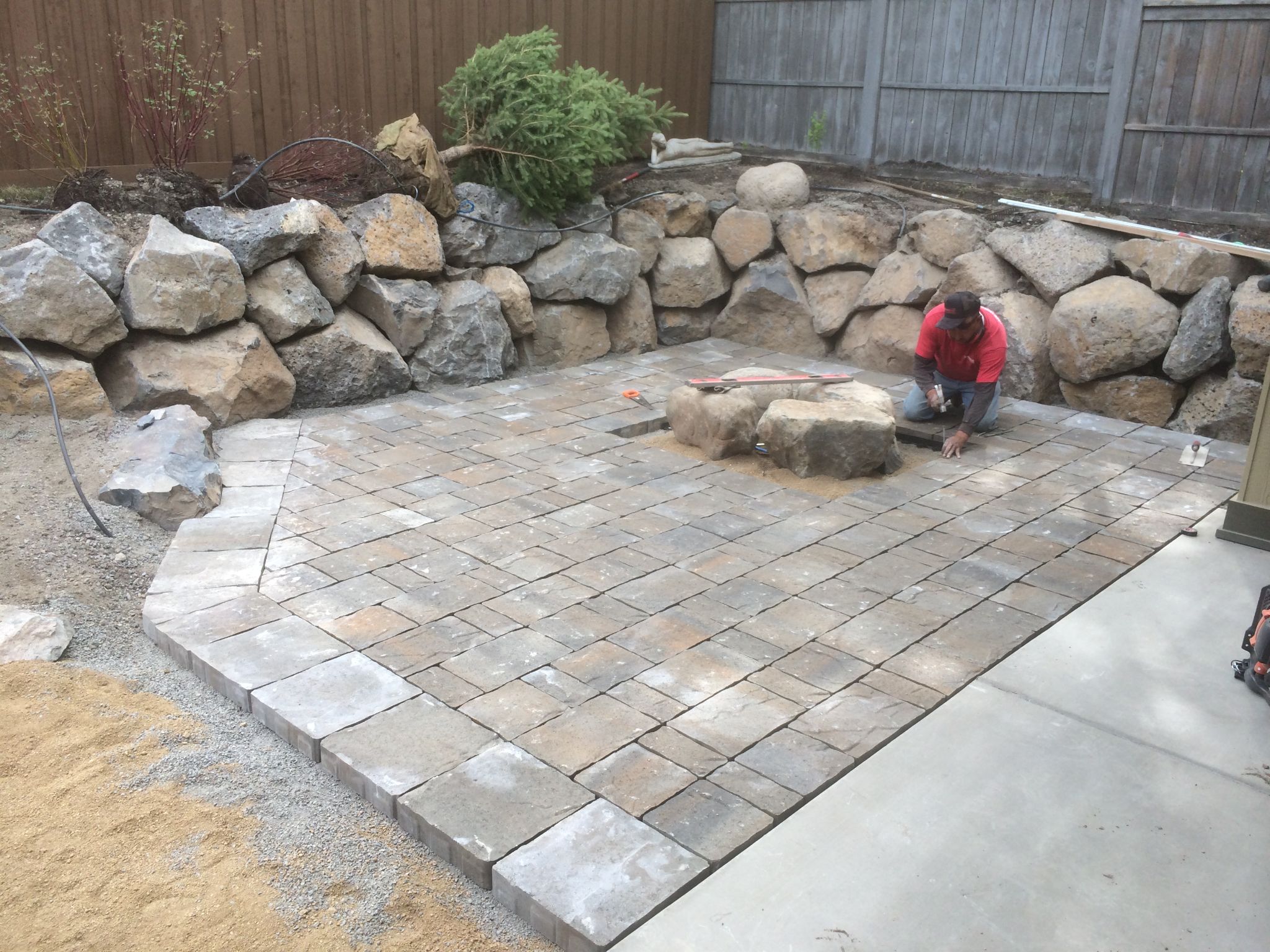 Paver installation in progress — boulder fire pit being set